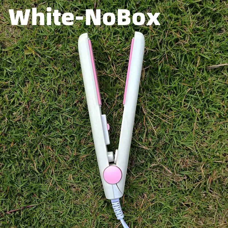 White hair straightener with pink accents lying on grass.