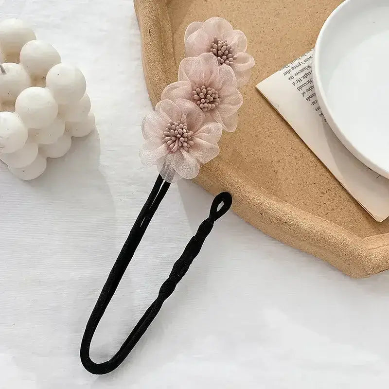 Hair accessory featuring three pale pink floral decorations attached to a black elastic band.