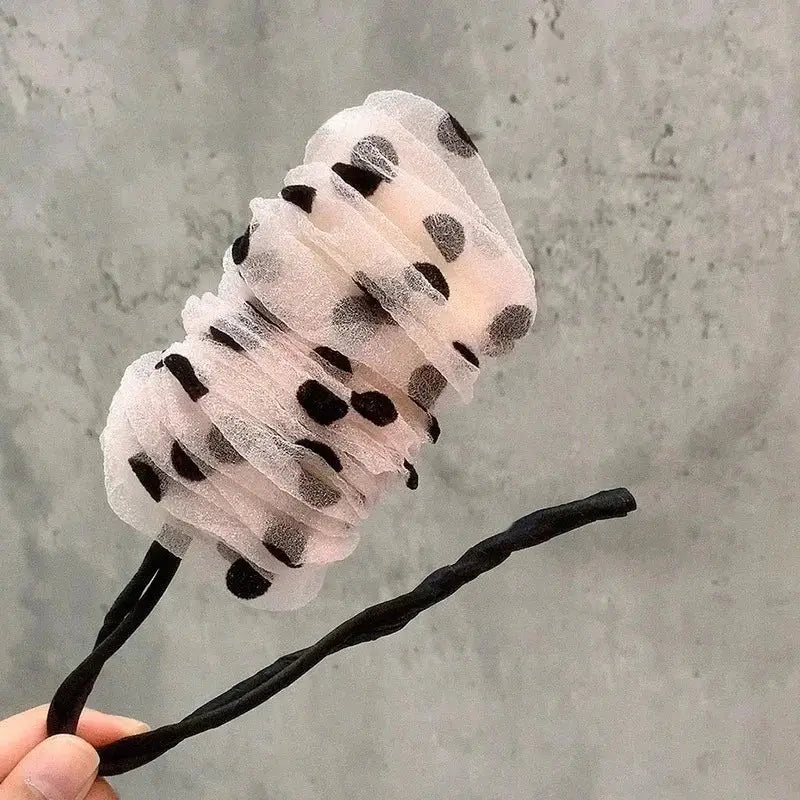 Cotton candy on a stick decorated with black spots to resemble a dalmatian pattern.