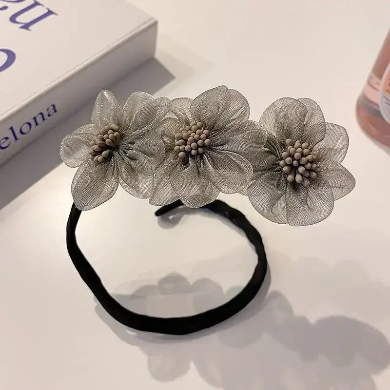 Hair tie adorned with three sheer fabric flowers in a silvery-gray color.