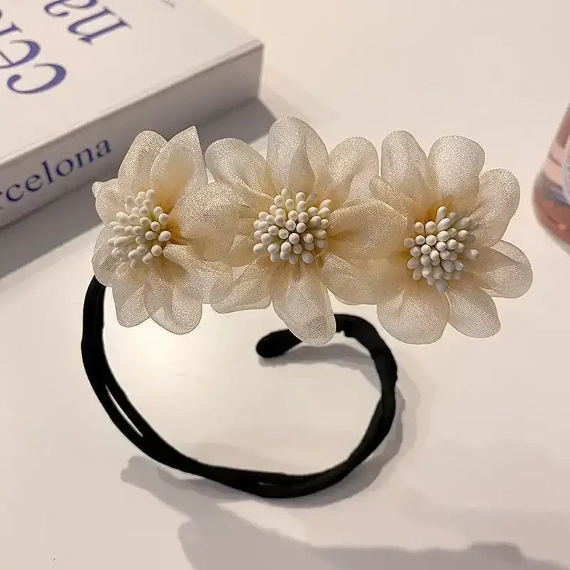 Hair tie adorned with three delicate white fabric flowers.