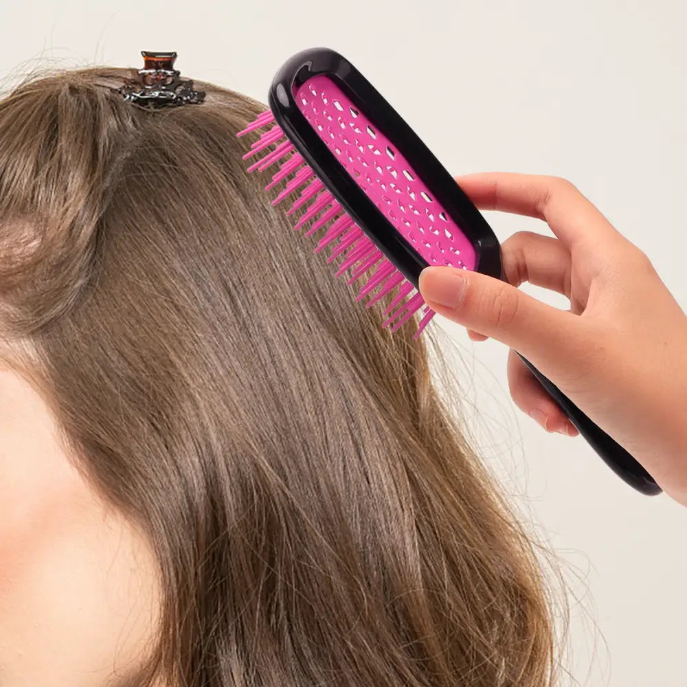 Pink and black hair straightening brush being used on long brown hair.