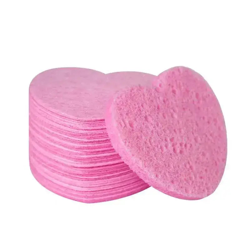 Stack of pink, circular facial cleansing pads with one pad leaning against the stack.