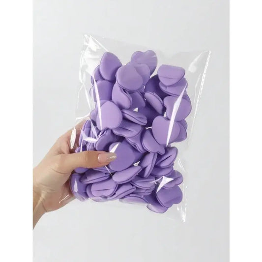 A clear plastic bag filled with purple heart-shaped confetti or decorations.