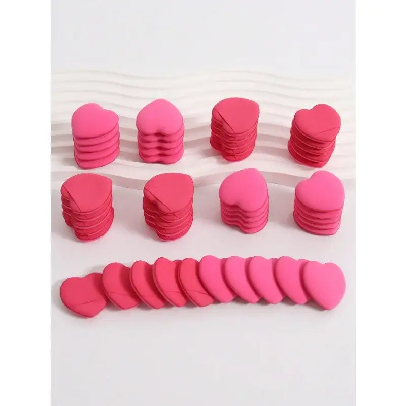 Pink heart-shaped makeup sponges arranged in rows.