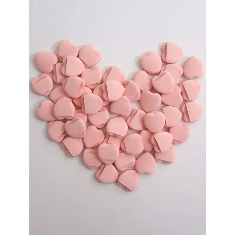 Heart shape formed by multiple small pink heart-shaped tablets or candies.