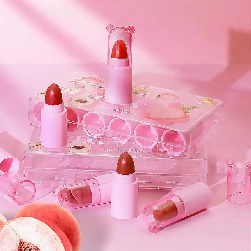 Pink lipsticks with bear-ear shaped caps on clear acrylic stands.