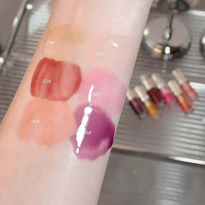 Swatches of various lip gloss or lipstick shades on skin.