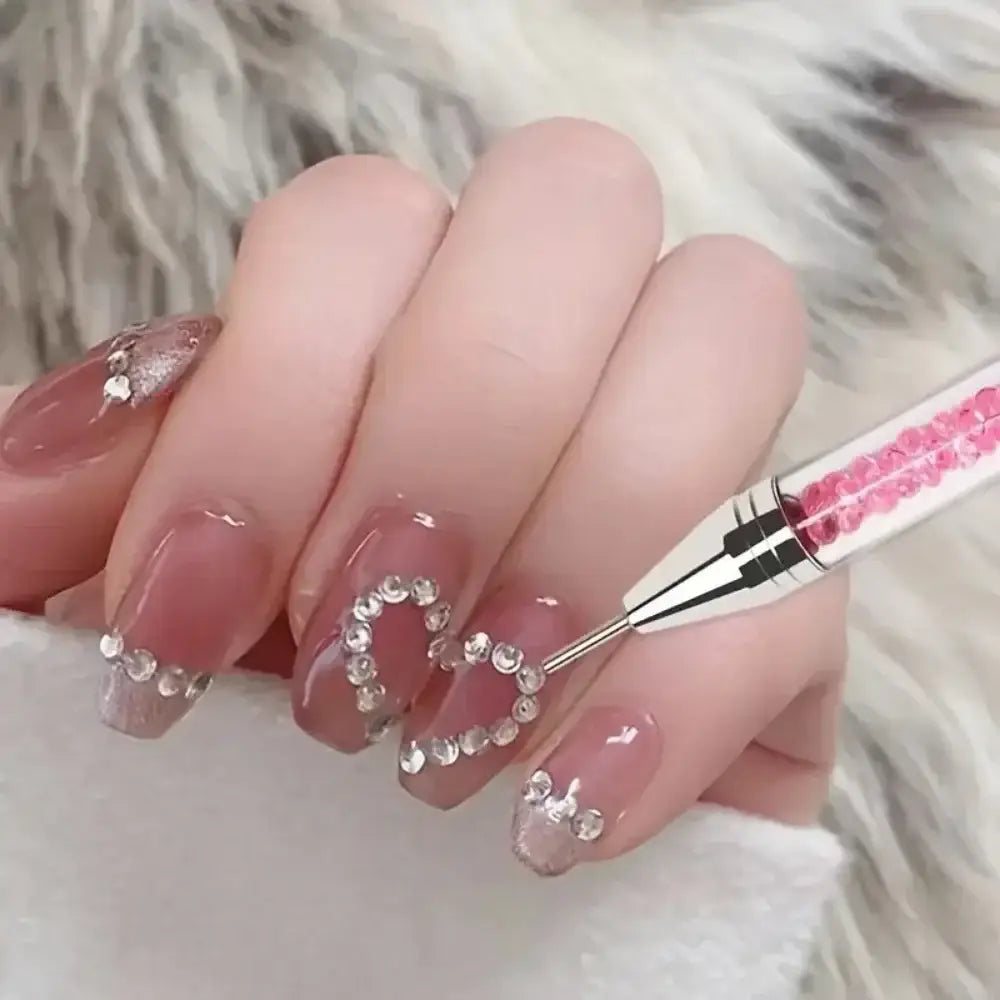 Manicured hand with long, pink nails adorned with rhinestone heart designs.