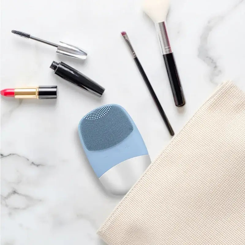 Blue and white facial cleansing brush with textured silicone surface.