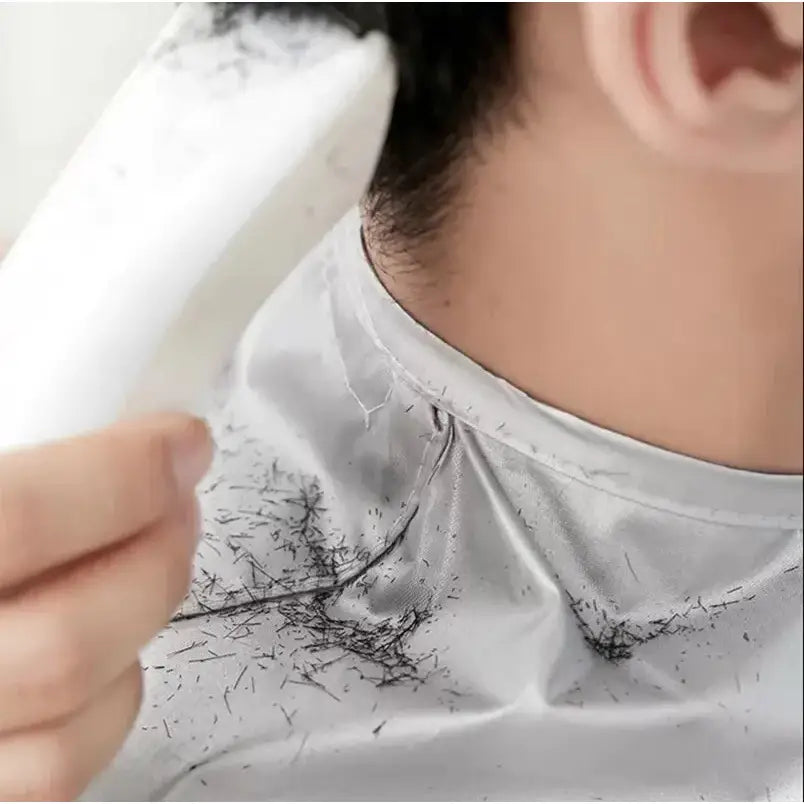 Hair-trimming device with cut hair clippings visible on a white shirt collar.