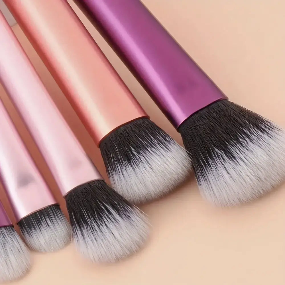 Makeup brushes with metallic pink and purple handles and soft, fluffy bristles.