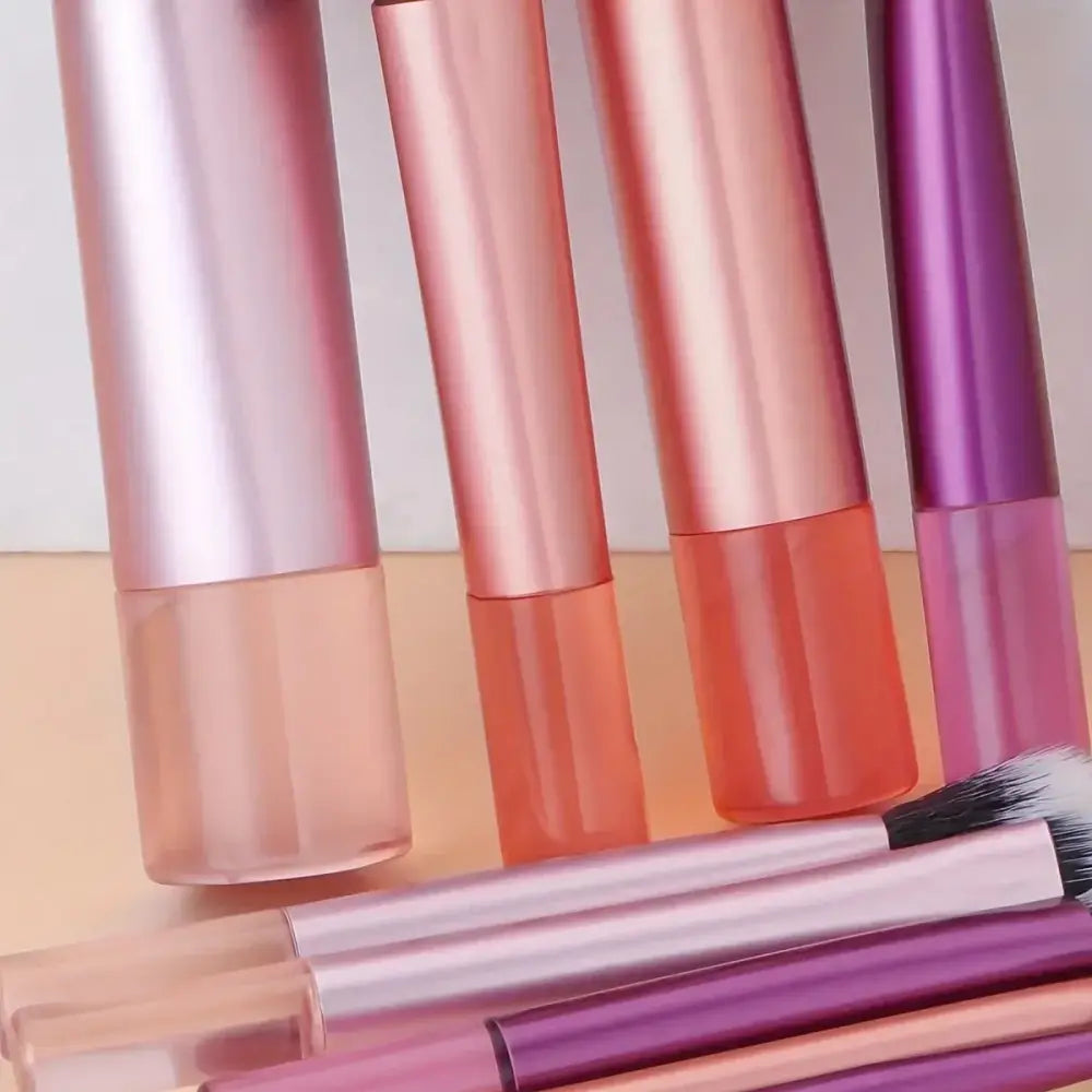 Collection of lip gloss tubes in various shades of pink and purple.