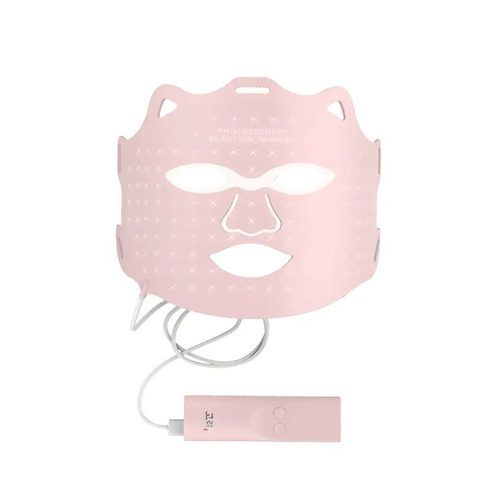 Pink facial mask with eye and mouth cutouts, connected to a small electronic device.