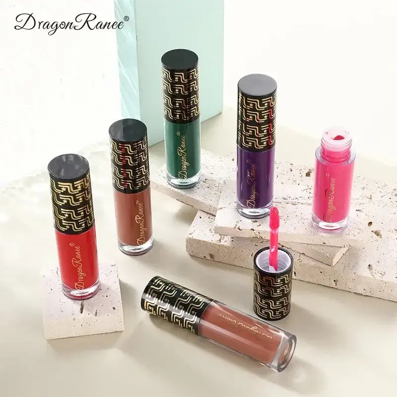 Collection of colorful liquid lipsticks or lip glosses with decorative gold-patterned caps.