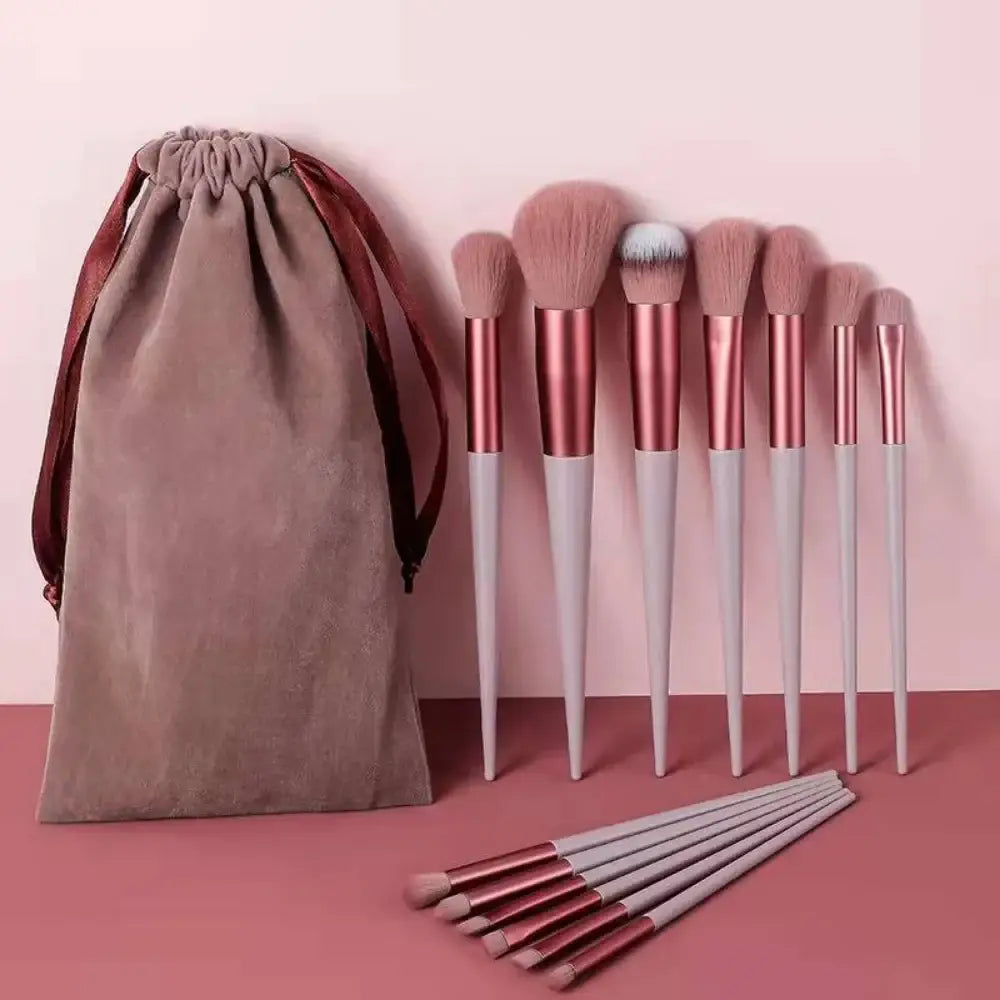 Set of makeup brushes with rose gold handles and a matching drawstring pouch.