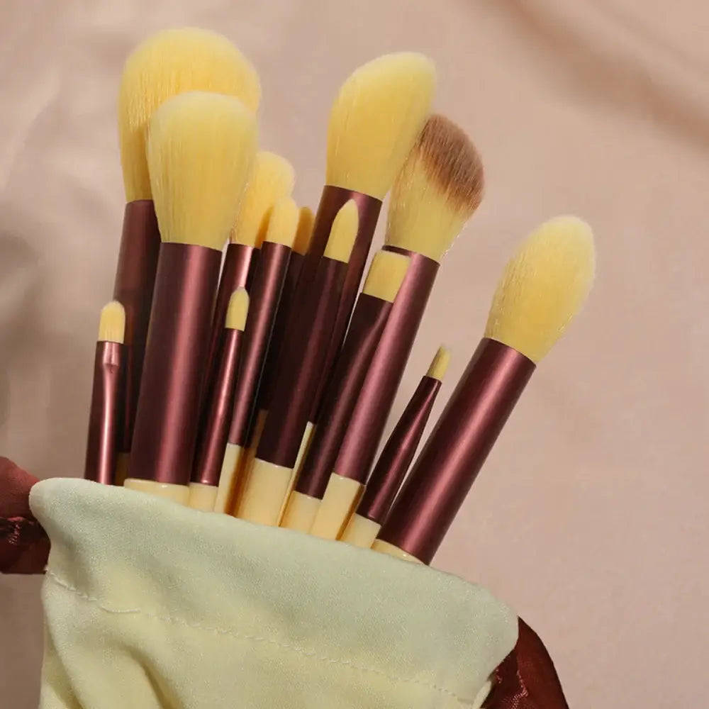 Set of makeup brushes with yellow bristles and burgundy handles.