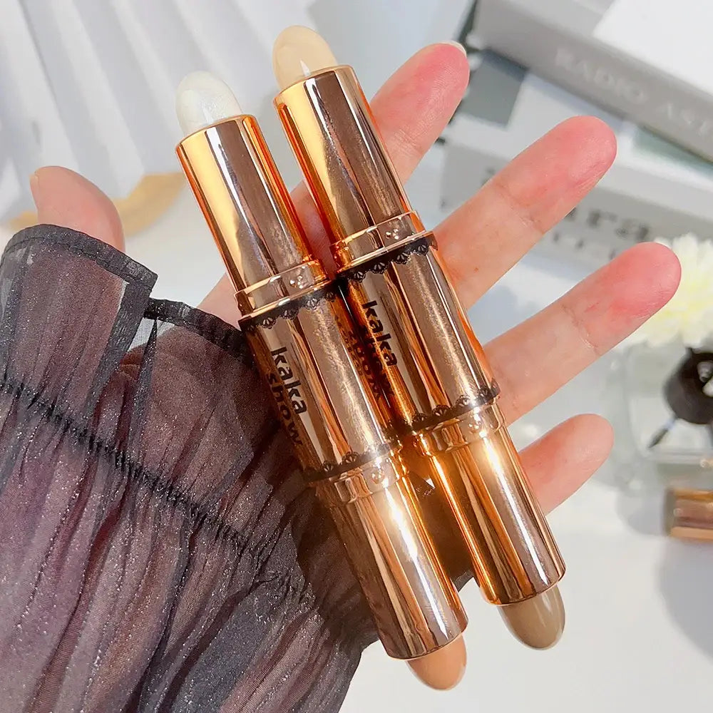 Two gold-colored lipstick or makeup tubes held in a hand.