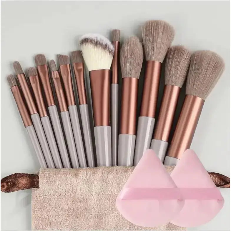 Set of makeup brushes with rose gold and silver handles arranged in a beige pouch.