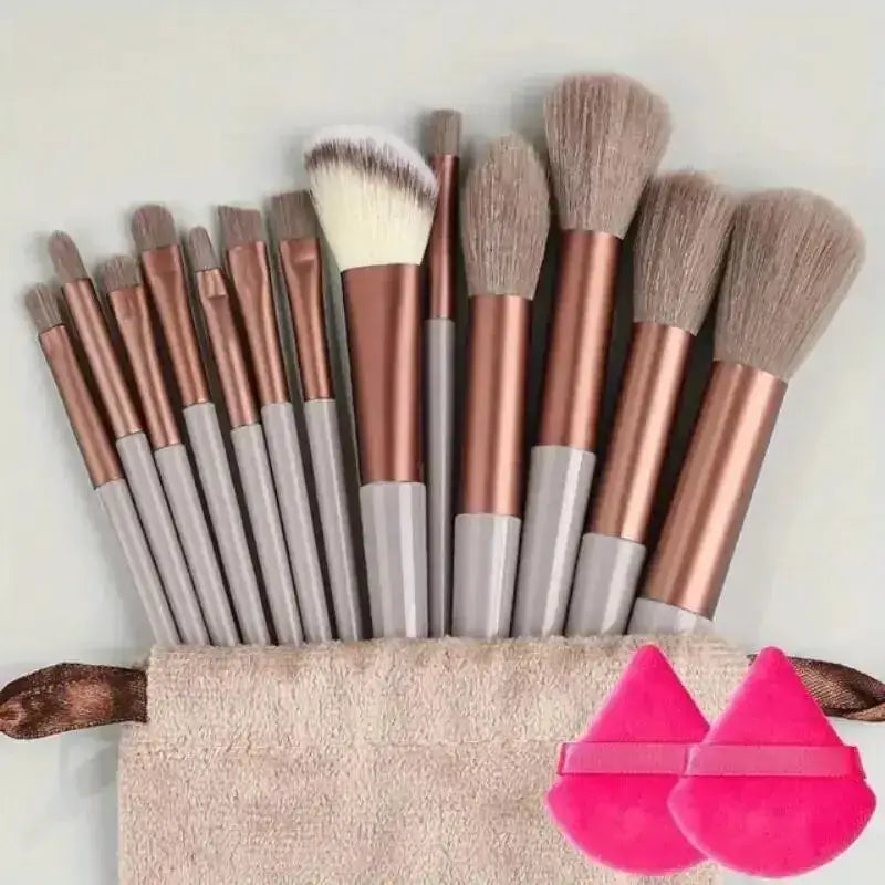 Set of makeup brushes with rose gold handles and a beige brush roll.