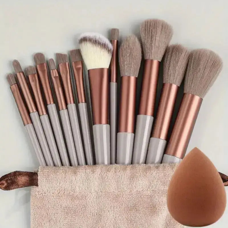 Set of makeup brushes with rose gold handles and a beauty blender sponge.