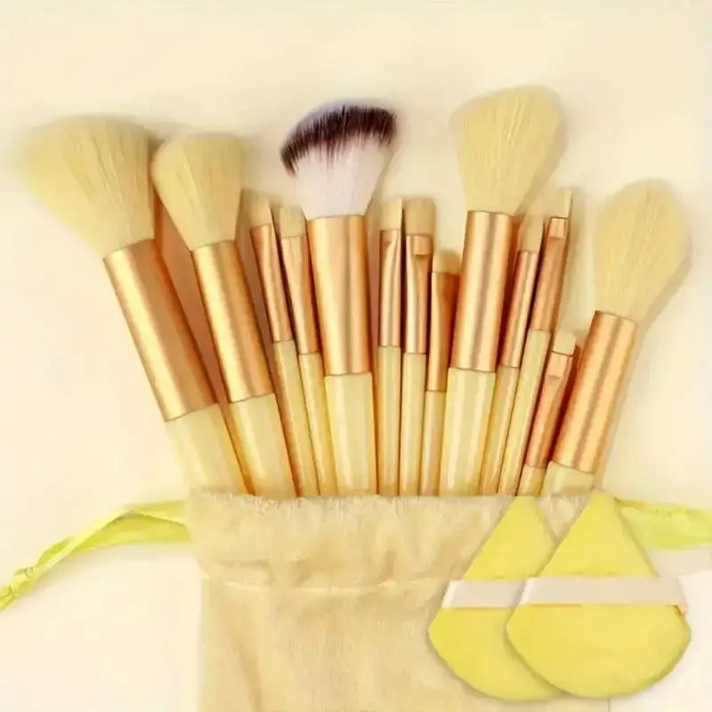 Set of makeup brushes with golden handles in a beige fabric holder.