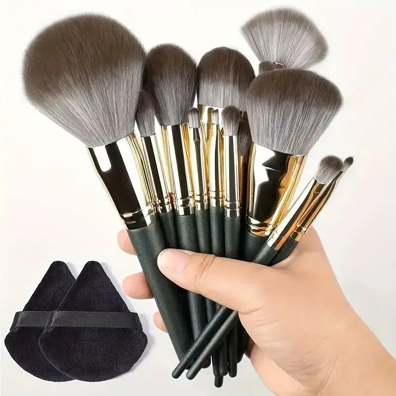 Set of makeup brushes with gray bristles and dark handles held in a hand.