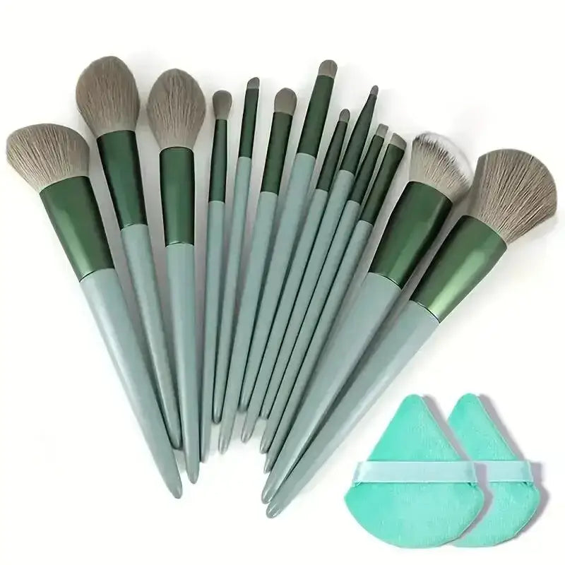 Set of makeup brushes with green and gray handles, accompanied by two mint-colored makeup sponges.