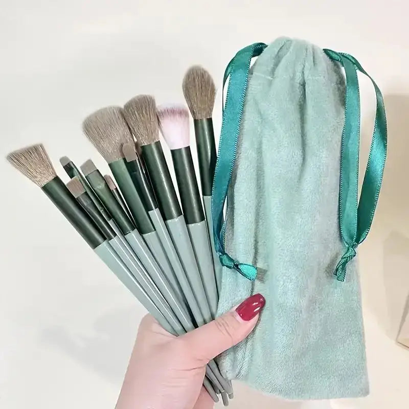 Set of makeup brushes with green handles and a matching teal velvet drawstring bag.