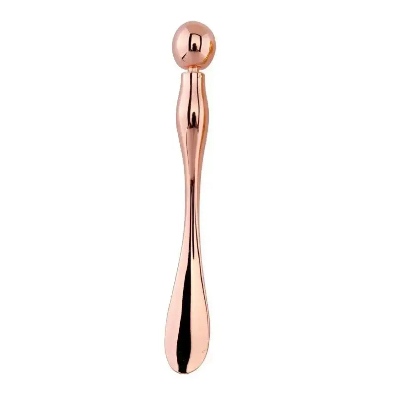 Rose gold-colored metallic massage tool with a teardrop-shaped end and spherical top.