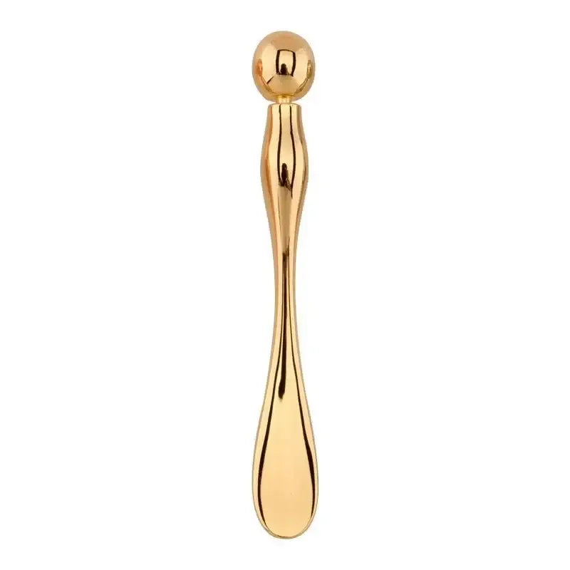 Golden metallic spoon or utensil with a long, slender handle and rounded end.