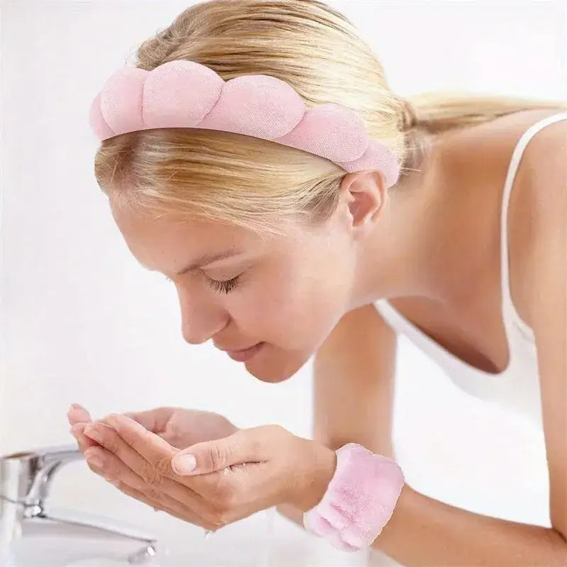 Woman washing her face over a sink, wearing a pink headband and wristband.