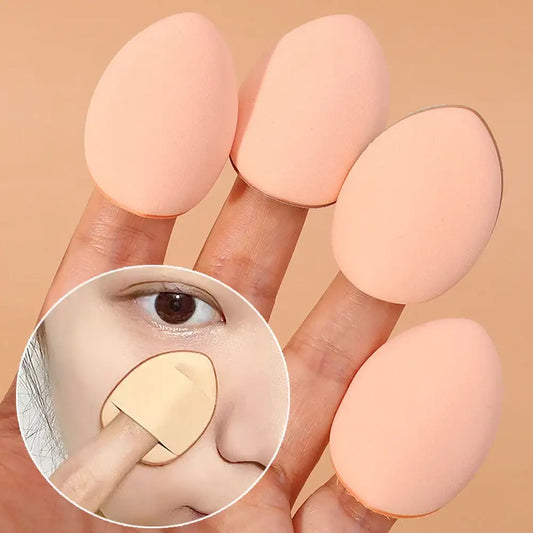 Makeup sponges on fingertips with a magnified view of application on skin.