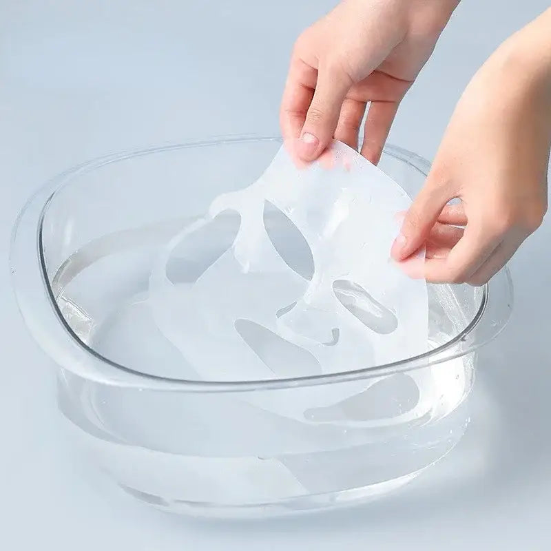 Hands placing a white skull-shaped object into a clear glass bowl filled with liquid.