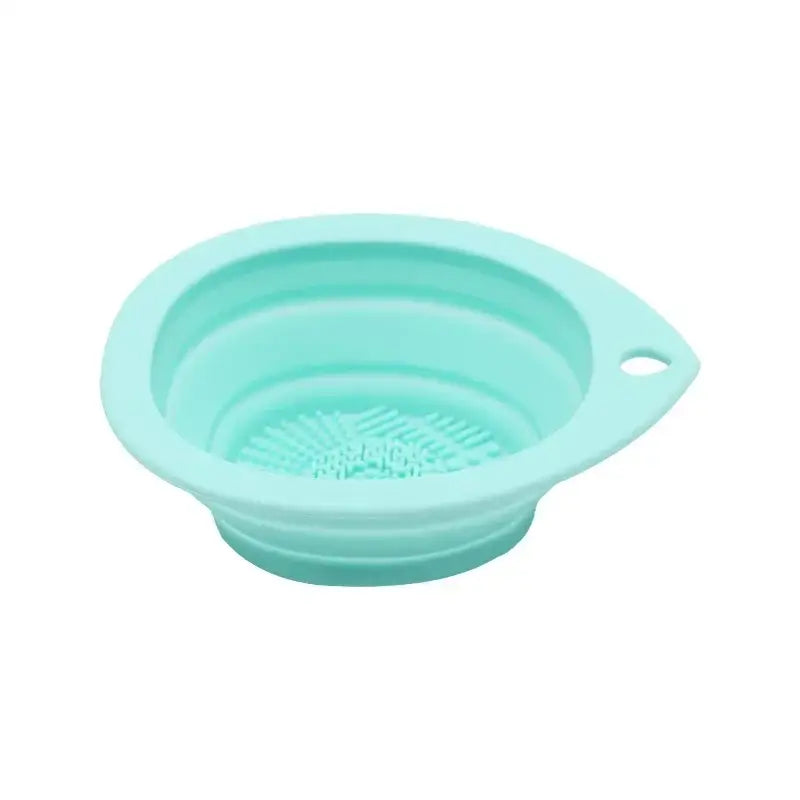 Mint green collapsible silicone bowl with ridged bottom and small handle.