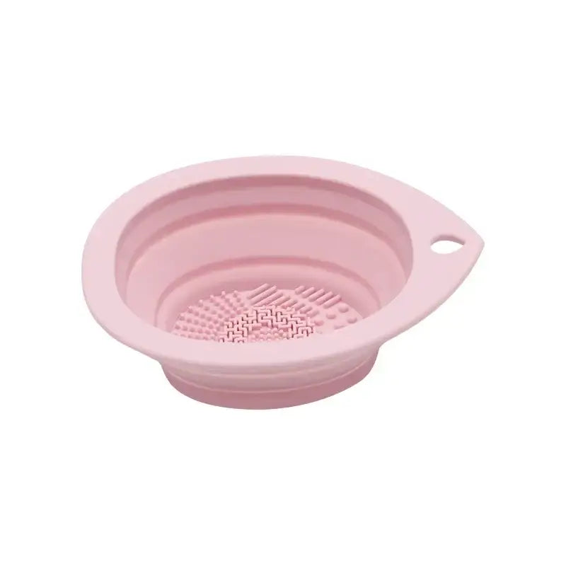 Pink silicone collapsible strainer with a textured bottom and small handle.