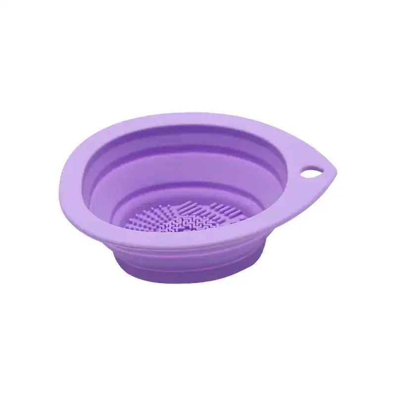 Purple silicone collapsible strainer with a textured bottom and small handle.