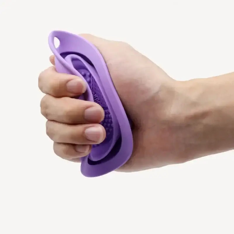 Purple silicone or rubber hand-held device with ridges, likely a massage or therapy tool.