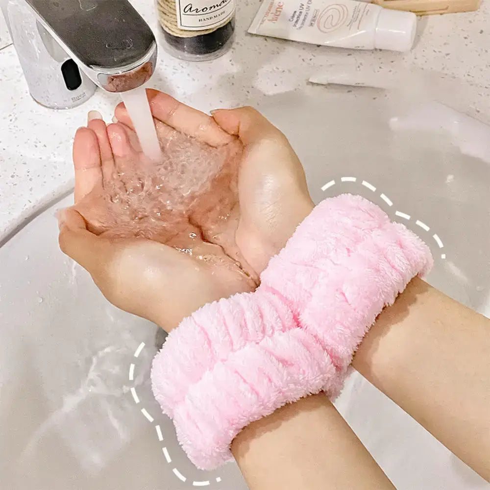 Hands cupped together holding water under a faucet, with a pink fuzzy scrunchie on one wrist.