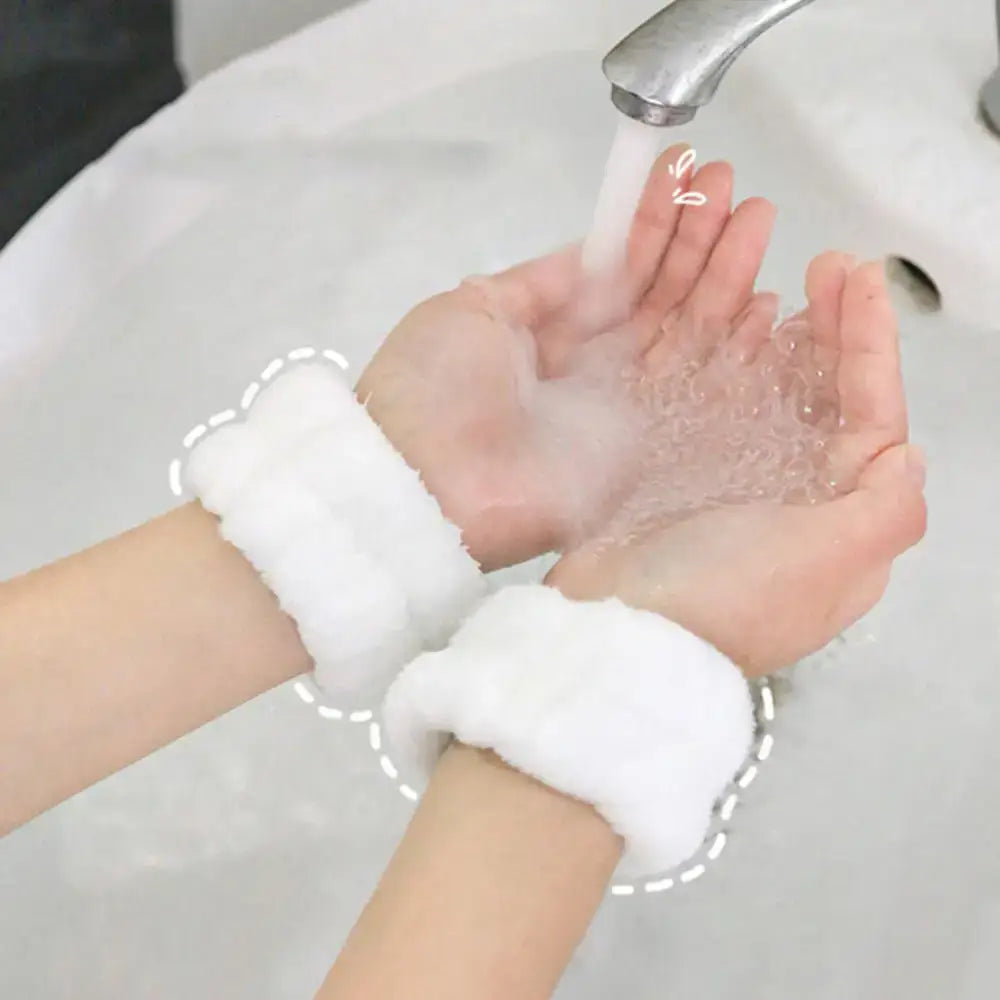 Hands wearing fluffy white wristbands washing under running water.