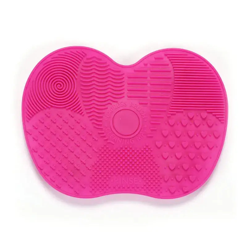 Hot pink silicone makeup brush cleaning mat with various textured sections.