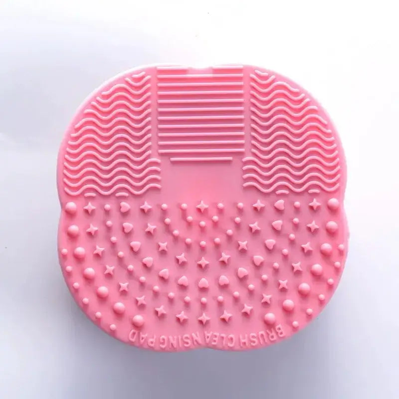 Pink silicone makeup brush cleaning pad with textured surfaces.