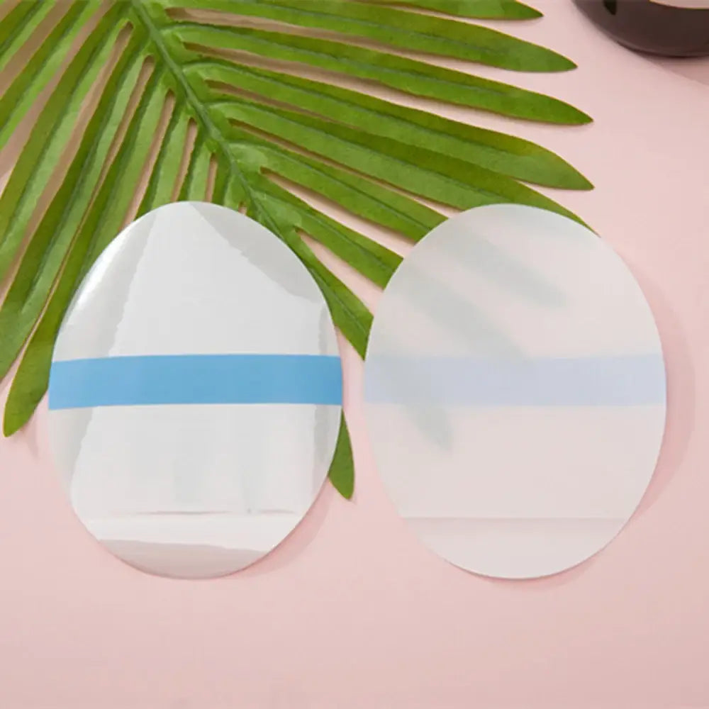 Two white, oval-shaped makeup sponges with one having a blue band around it.