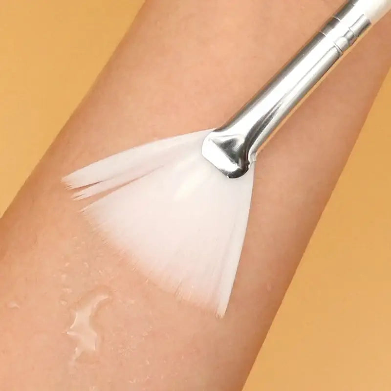 Makeup brush applying white powder or foundation to skin.