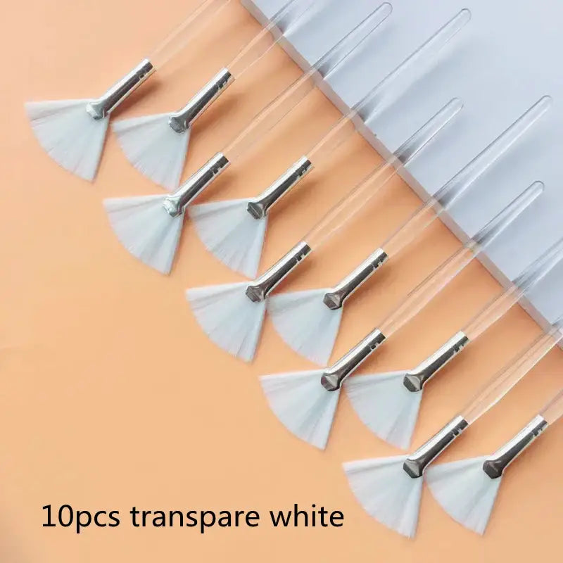 Set of ten transparent white fan-shaped makeup brushes with metal handles.