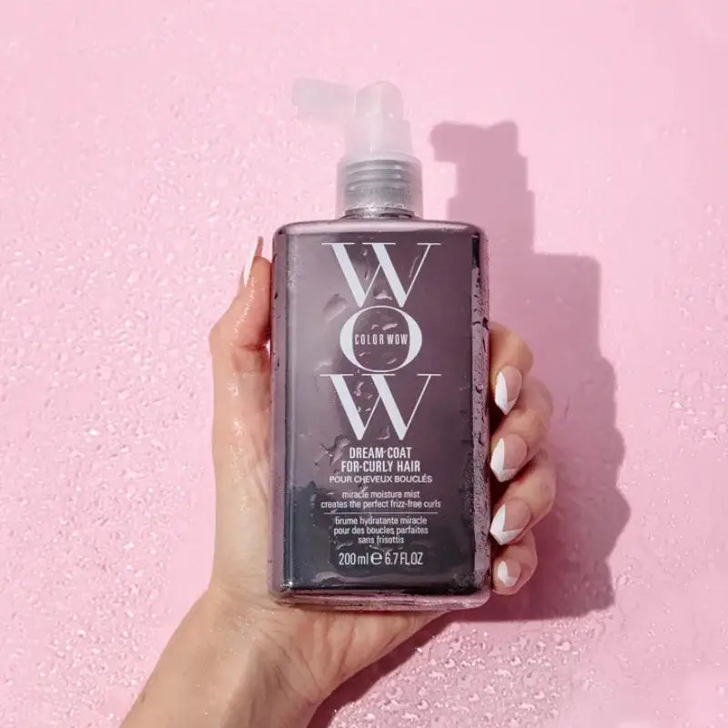 Bottle of ’WOW’ brand hair care product held by a hand.